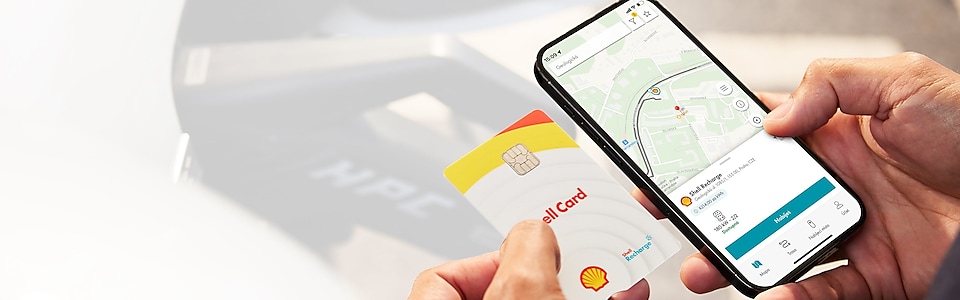 Ruce drží Shell kartu a mobil s Recharge aplikací s navigací k nejbližší stanici
